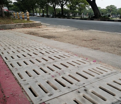 Grey rectangular FRP manhole cover installed flush on pavement.