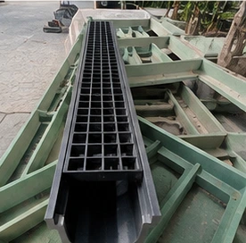 Long outdoor drainage trench fitted with a black FRP grating.