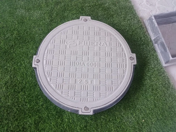 White round FRP manhole cover with anti-slip surface texture on grass.